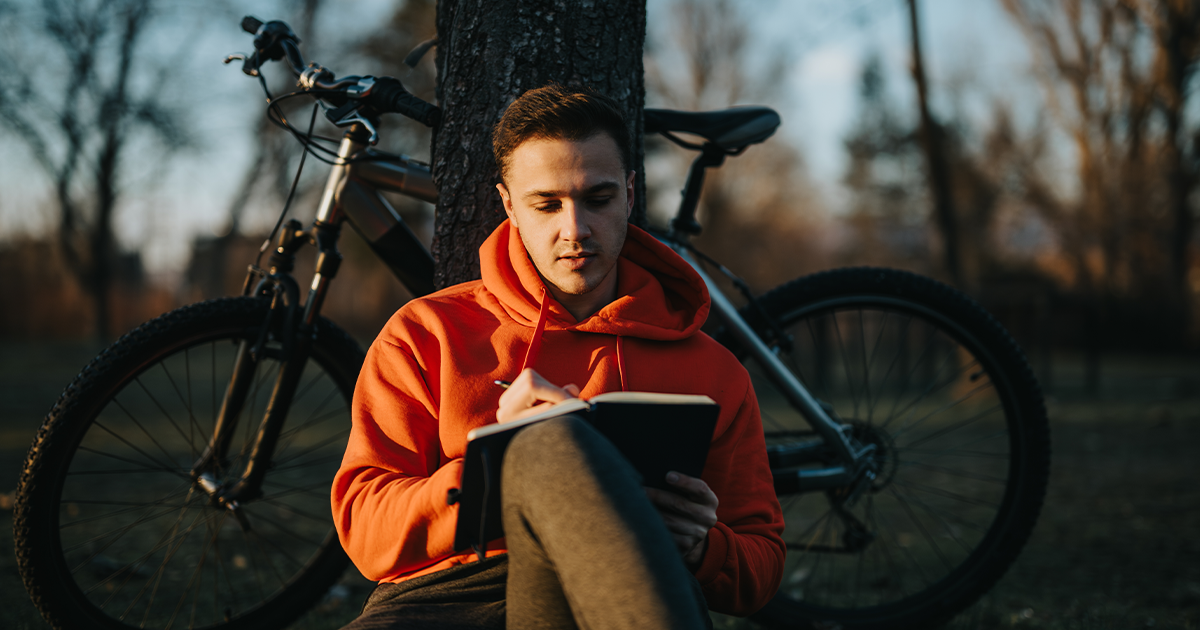 Man journaling under a tree.