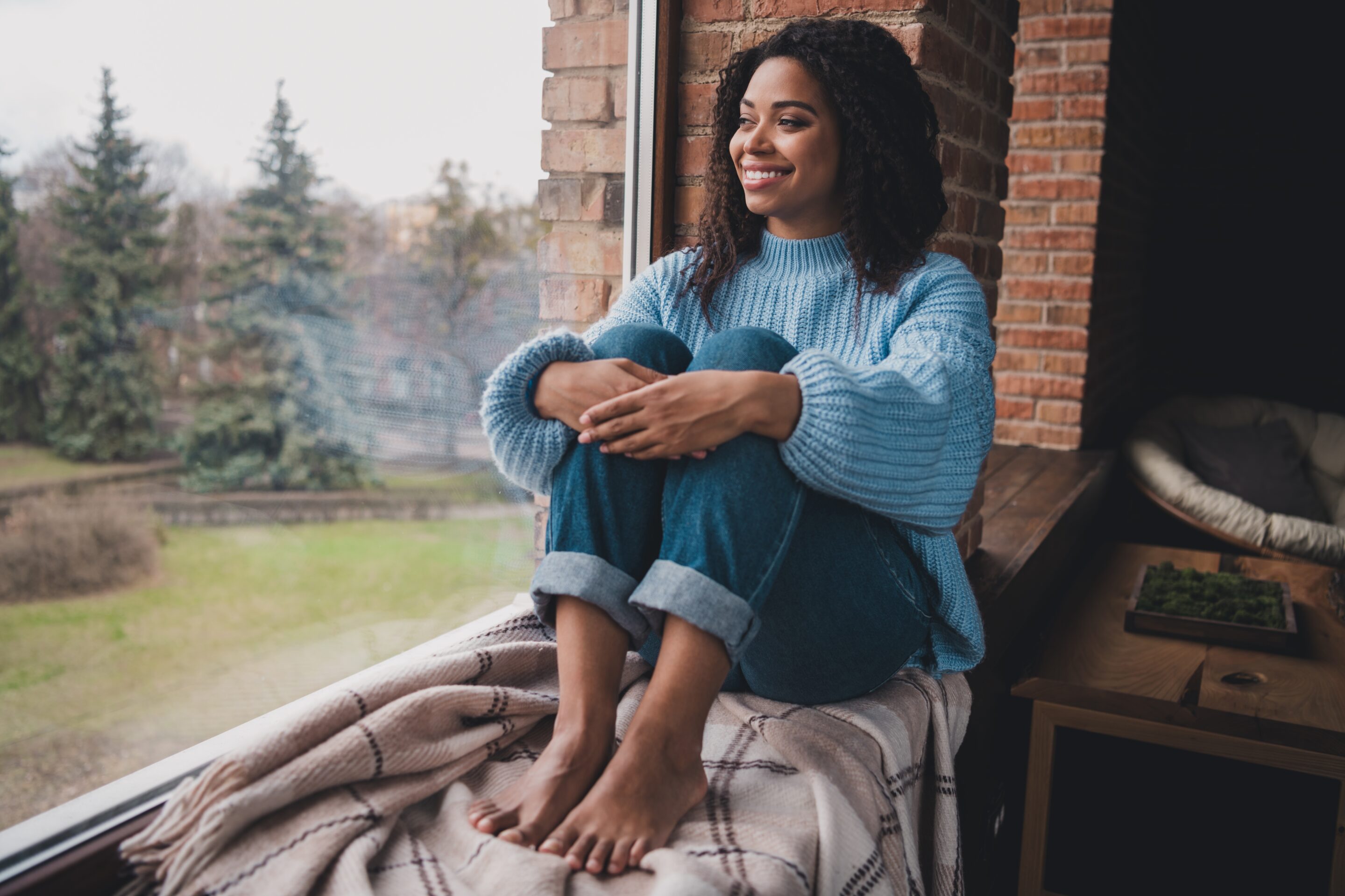 Woman sitting on window ledge looking out window contemplating medication management for anxiety and depression