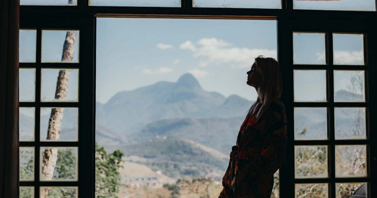 Silhouetted woman standing by an open doorway looking out at distant mountains