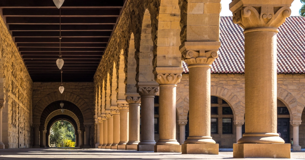 Stone archway with tall columns and warm sunlight illuminating the walkway.