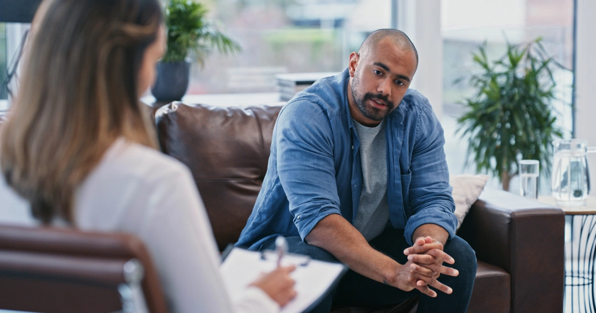 Man sitting on a couch talking with a therapist during a counseling session