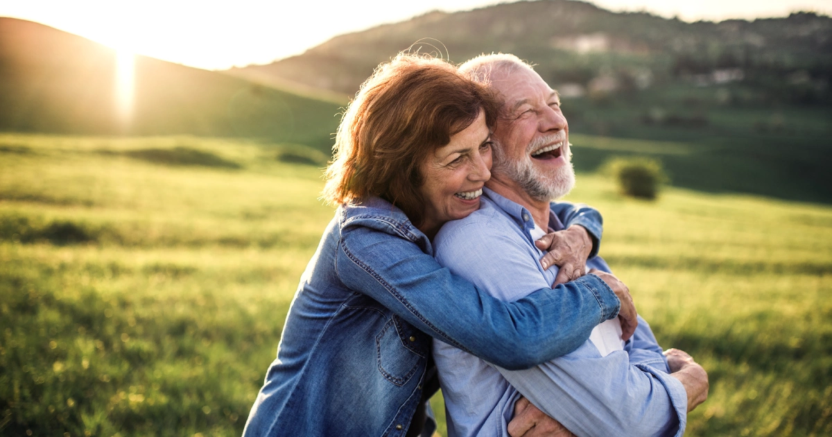 Smiling older couple embracing outdoors in a sunny open field