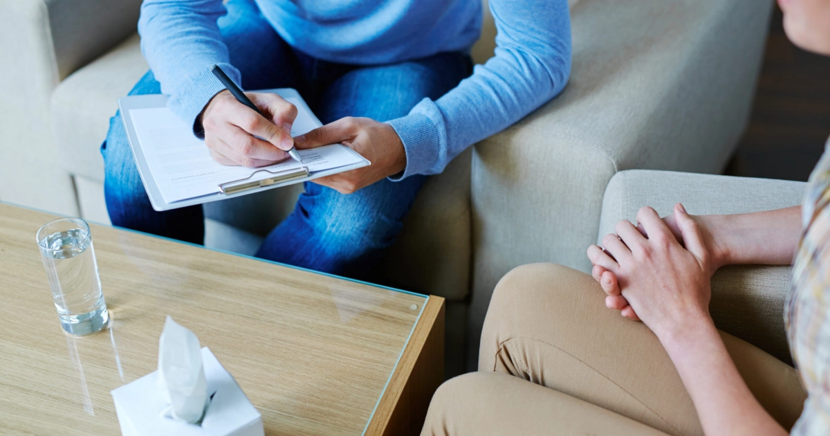 Therapist taking notes while talking with a client during a counseling session