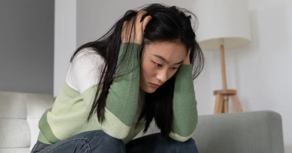 Anxious worried asian millennial girl holding head