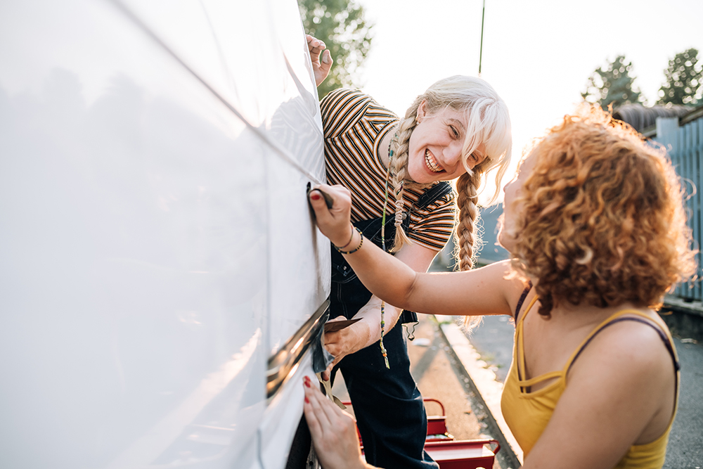 Young female couple working on their van